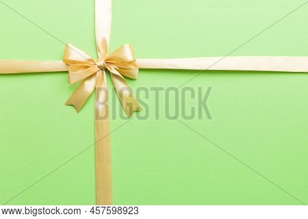 Top View Of Gold Ribbon Rolled And Yellowbow Isolated On Colored Background. Flat Lay With Copy Spac