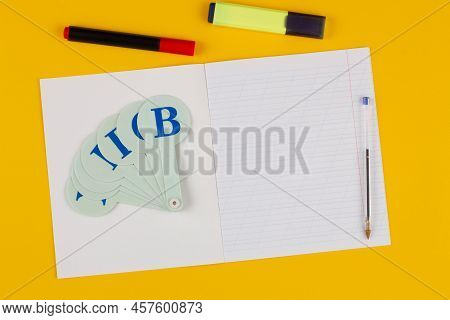 School Notebook On A Yellow Background With Copy Space For Text, Colorful Markers, English Alphabet.