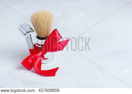 Father's Day Gift Concept: Safety Razor And Shaving Brush With A Red Ribbon Bow Isolated On A Concre