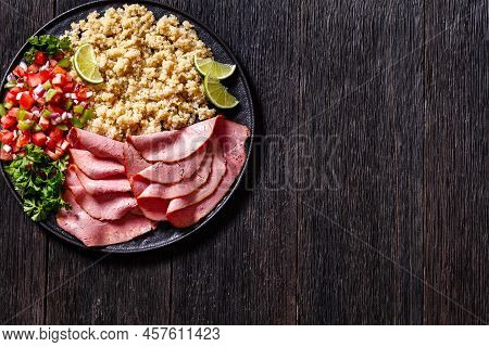 Thinly Sliced Roast Beef Fillet With Quinoa And Tomato Pepper Salsa On Black Plate On Dark Wooden Ta