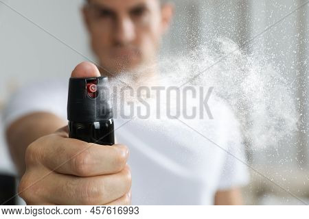 Man Using Pepper Spray At Home, Focus On Hand