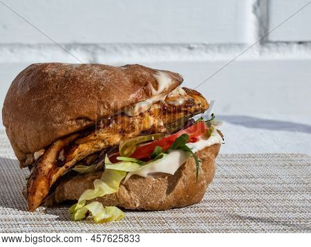 Close-up Shot Of Juicy Chicken Burger With Grilled Chicken Fillet, Ciabata, Burger Sauce, Arugula, P