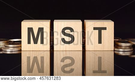 Mst Text On Wood Cubes With Coins, Black Background, Business Concept. The Inscription On The Cubes 