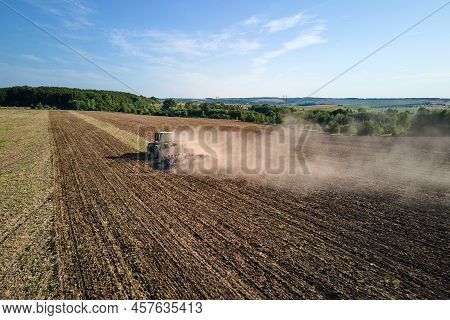 Aerial View Of Tractor Plowing Agriculural Farm Field Preparing Soil For Seeding In Summer