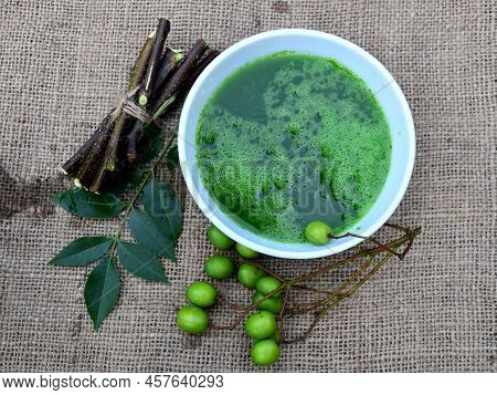 Neem Leaves, Fruits, And Branches On Jute Fabric Background. Neem Medicinal Herb Juice In Bowl. Neem