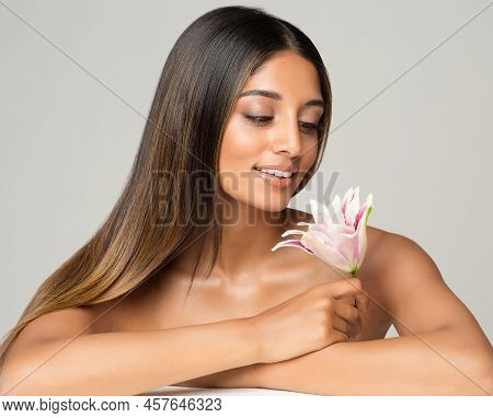 Beauty Brunette Model With Long Silk Shiny Hairstyle. Beautiful Woman Looking At Flower Relaxing In 
