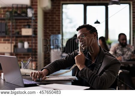Company Employee With Physical Disability Talking On Landline Phone Call, Using Office Telephone At 