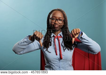 Dissapointed Young Adult Superhero Woman Giving Thumbs Down Dissaproval Fingers Gesture While Lookin