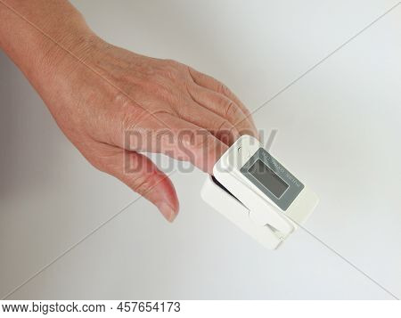 Woman Using Modern Fingertip Pulse Oximeter On Light Background, Closeup. Woman Hand With Fingertip 