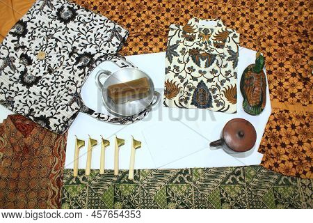 Flat Lay Batik Clotes With Canting, Small Pan And Wax Earthenware Glass Isolated On White Background