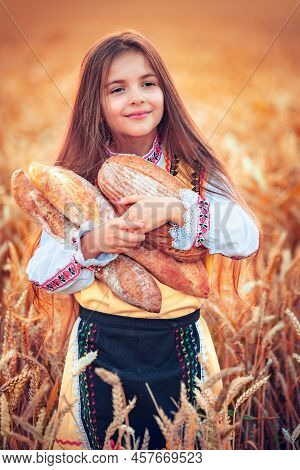 Beautiful Girl Woman In Traditional Bulgarian Folklore Dress Holding Homemade Bread In Wheat Field
