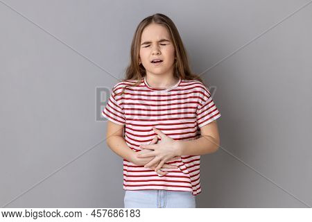 Portrait Of Little Girl Wearing Striped T-shirt Clutching Belly, Feeling Discomfort Or Pain In Stoma