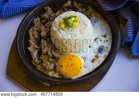 Breakfast With Rice, Fried Egg And Meat Or Beef With Garnish Corn And Leek Close Up Hot Plate Isolat