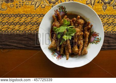 Spicy Chicken Feet With Celery, Chili, Onion, Garlic Served With A White Plate Isolated From A Black