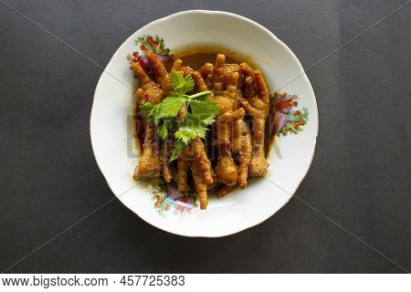 Spicy Chicken Feet With Celery, Chili, Onion, Garlic Served With A White Plate Isolated From A Black