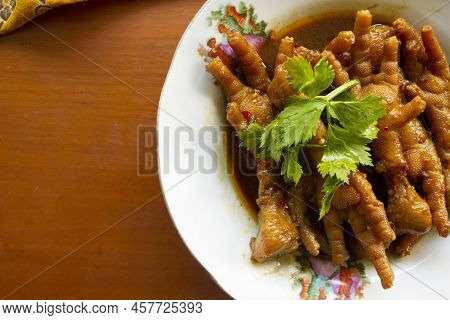 Spicy Chicken Feet With Celery, Chili, Onion, Garlic Served With A White Plate Isolated From A Black