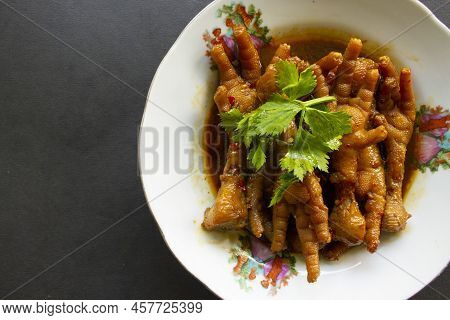 Spicy Chicken Feet With Celery, Chili, Onion, Garlic Served With A White Plate Isolated From A Black