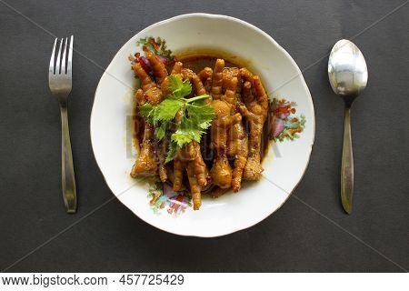 Spicy Chicken Feet With Celery, Chili, Onion, Garlic Served With A White Plate Isolated From A Black