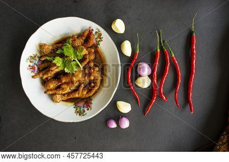 Spicy Chicken Feet With Celery, Chili, Onion, Garlic Served With A White Plate Isolated From A Black