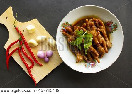 Spicy Chicken Feet With Celery, Chili, Onion, Garlic Served With A White Plate Isolated From A Black