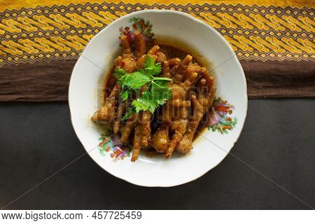 Spicy Chicken Feet With Celery, Chili, Onion, Garlic Served With A White Plate Isolated From A Black