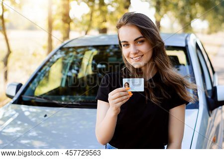 Attractive Young Woman Wearing Black T-shirt Standing In Front Of Modern Car Bragging About Receivin
