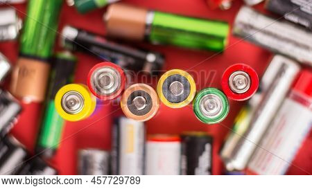 Background Of Batteries Of Different Size And Firm`s On A Red Background. Symbol Of Power. Ecologica