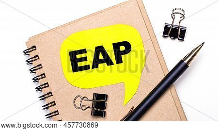On A Light Background, A Brown Notebook, A Black Pen And Paper Clips, And A Yellow Card With The Tex