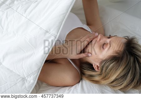 Woman Looks In Shock Under Covers In Bed. Bedwetting In Women Concept