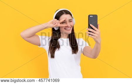 Positive Lady In White Shirt In Headphones Making Selfie On Phone With Peace Gesture, Selfie