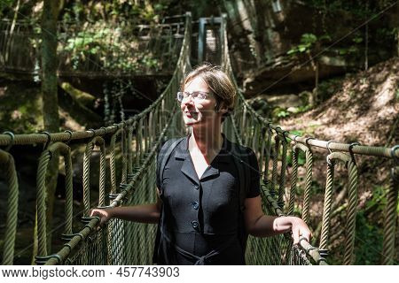 Portrait Of A Woman At A Wooden Suspension Bridge Over A Small Creek Valley In The Woods, Kordel, Be