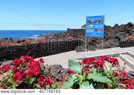 Garachico, Tenerife, Canary Islands, Spain, July 6, 2022: Flowers Next To A Sign With Tourist Inform