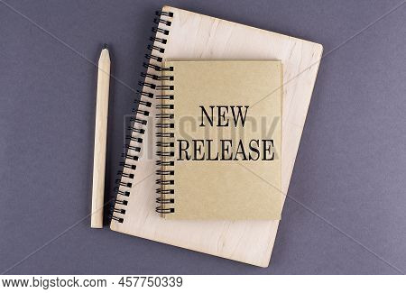 Word New Release On A Notebook With Pencil On The Grey Background