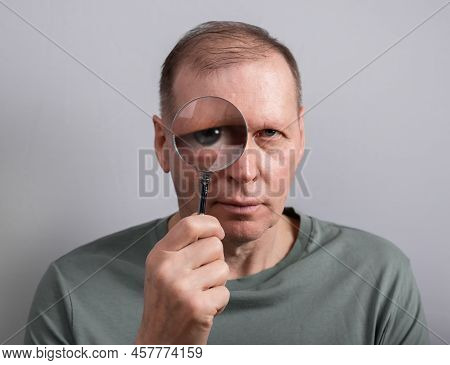 Man Looking Through Magnifying Lens Glass Portrait. High Quality Photo
