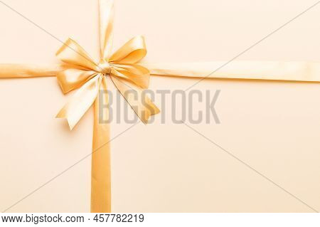 Top View Of Gold Ribbon Rolled And Yellowbow Isolated On Colored Background. Flat Lay With Copy Spac