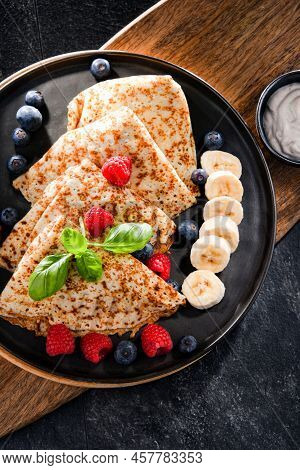 A Plate Of Pancakes With Cheese And Fruits