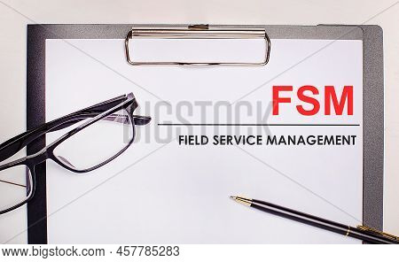On A Light Wooden Background Glasses, A Pen And A Sheet Of Paper With The Text Fsm Field Service Man