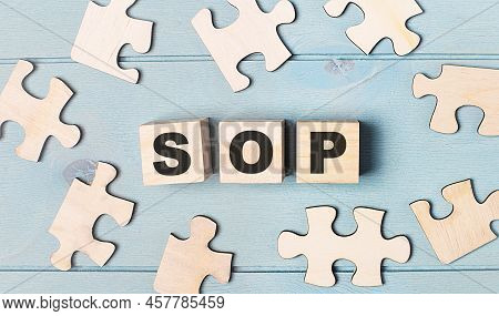 Blank Puzzles And Wooden Cubes With The Text Sop Standard Operating Procedure Lie On A Light Blue Ba