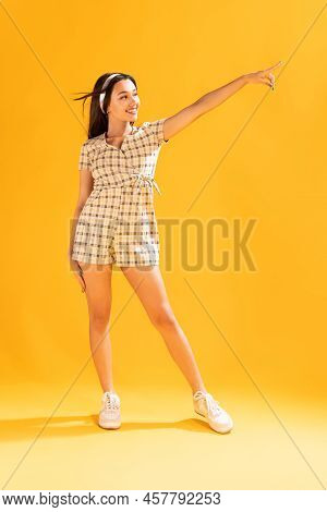 Full-lengfth Portrait Of Beautiful, Stylish, Young Girl Posing, Smiling Isolated Over Yellow Studio 
