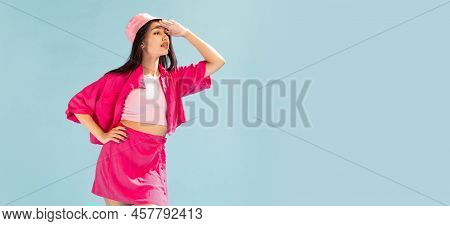 Portrait Of Beautiful Young Girl In Pink Panama Posing, Looking Away Isolated Over Light Blue Studio