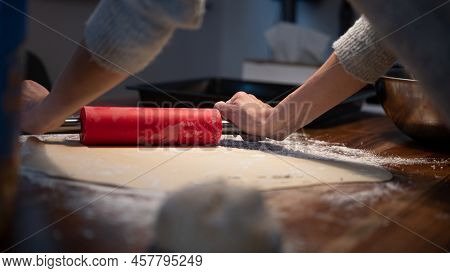 Low Angle View Of A Woman Using Red Rolling Pin To Roll Homemade Vegan Pastry Dough For Strudel Or P