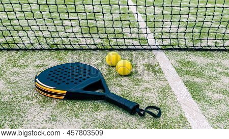 Yellow Balls On Grass Turf Near Padel Tennis Racket Behind Net In Green Court