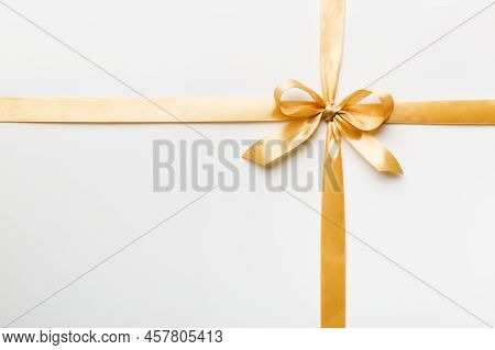 Top View Of Gold Ribbon Rolled And Yellowbow Isolated On Colored Background. Flat Lay With Copy Spac