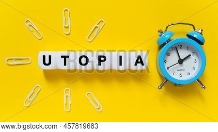 Finance And Economics Concept. On A Yellow Background, A Blue Alarm Clock, Paper Clips And White Cub