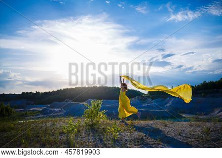 Happy Ukrainian Woman Running In Nature. In A Long Yellow Dress. Symbol Of Freedom Of Ukraine. Woman