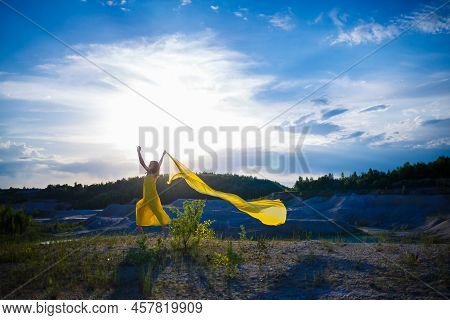 Happy Ukrainian Woman Running In Nature. In A Long Yellow Dress. Symbol Of Freedom Of Ukraine. Woman