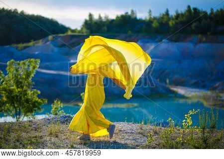 Happy Ukrainian Woman Running In Nature. In A Long Yellow Dress. Symbol Of Freedom Of Ukraine. Woman