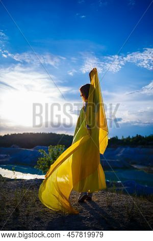 Happy Ukrainian Woman Running In Nature. In A Long Yellow Dress. Symbol Of Freedom Of Ukraine. Woman