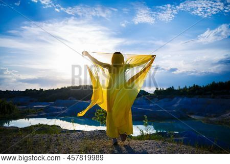Happy Ukrainian Woman Running In Nature. In A Long Yellow Dress. Symbol Of Freedom Of Ukraine. Woman