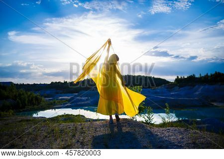 Happy Ukrainian Woman Running In Nature. In A Long Yellow Dress. Symbol Of Freedom Of Ukraine. Woman